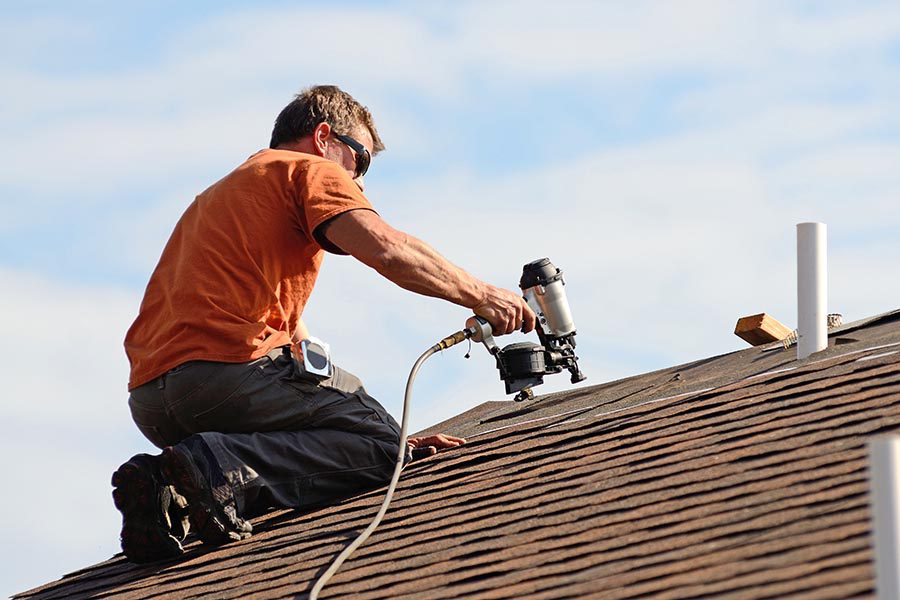 Specialized Business Insurance - Roofer Works on a Sunny Day Using a Nail Gun